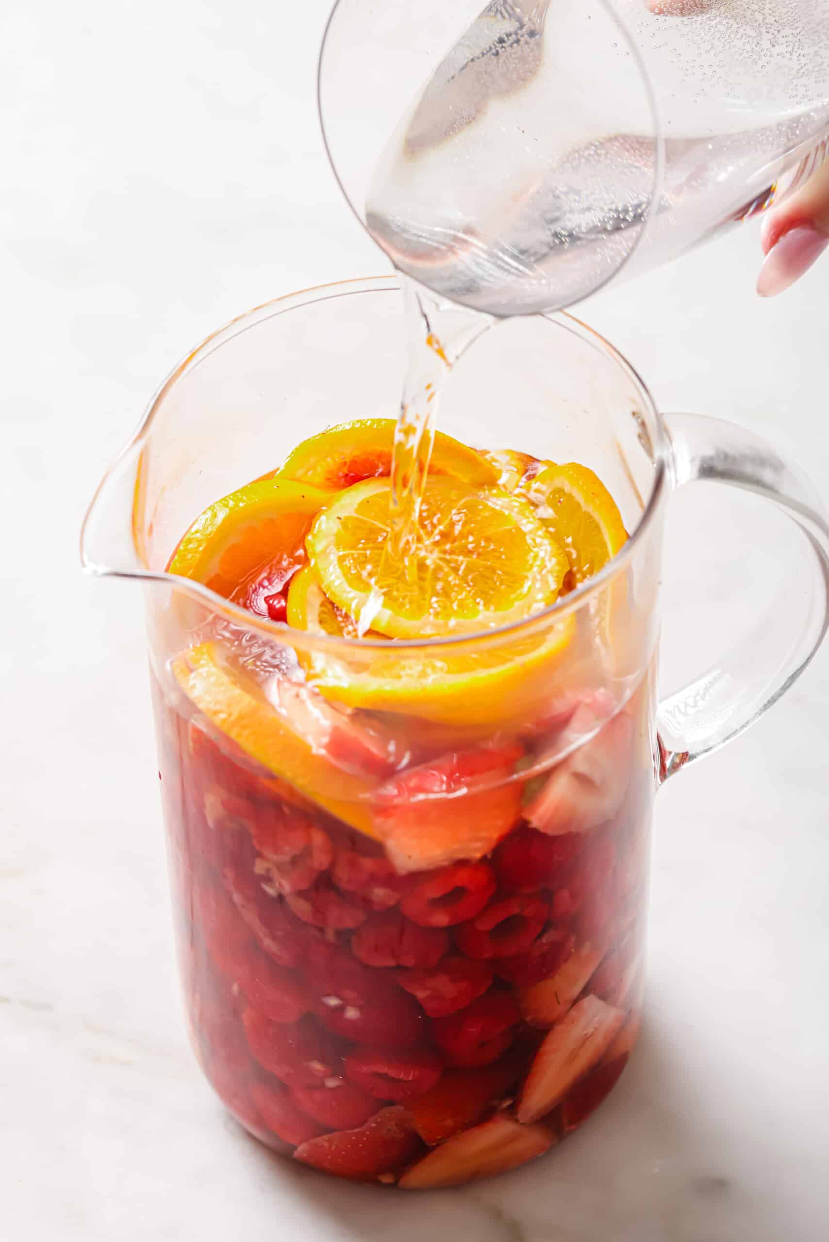 Pouring sparkling water into the pitcher.