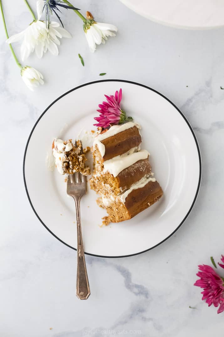 a slice of The BEST Hummingbird Cake Recipe with Light Cream Cheese Frosting on a plate with a fork