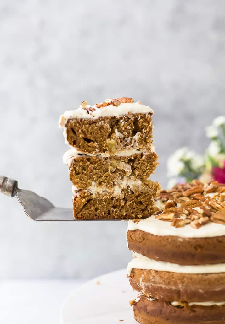 a slice of The BEST Hummingbird Cake Recipe with Light Cream Cheese Frosting being pulled out from the cake and ready to serve