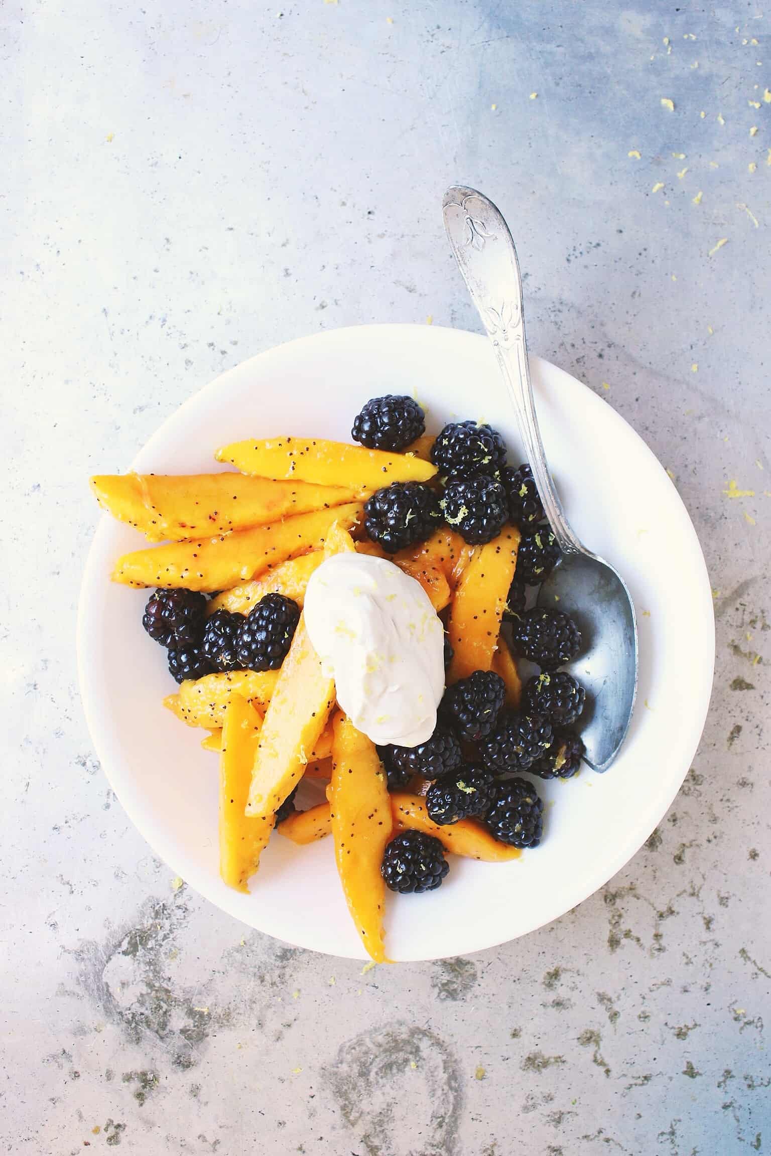 A Mango Blackberry Lemon Poppyseed Fruit Salad in a Bowl with a Spoon