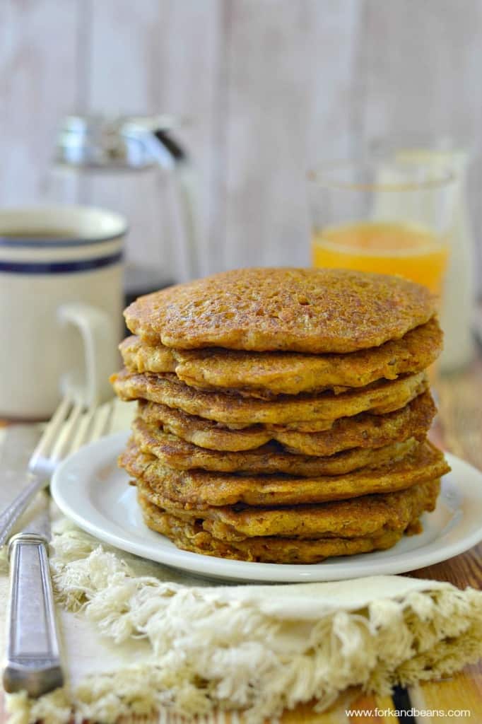 A Stack of Carrot Cake Pancakes Next to a Glass of Orange Juice