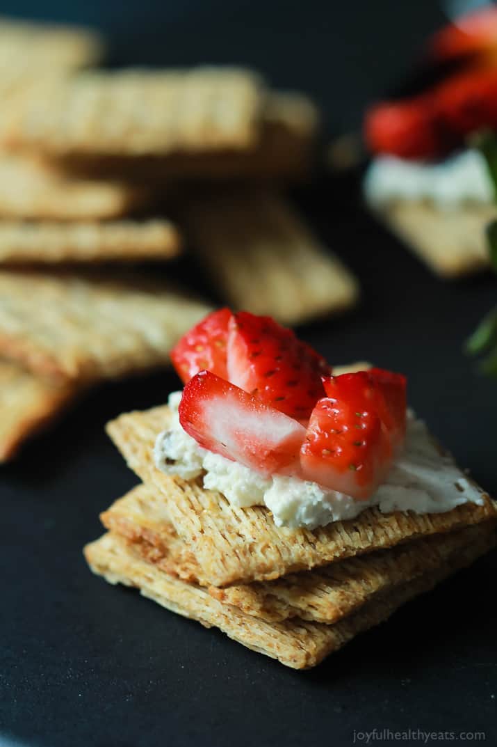 A stack of Triscuits topped with goat cheese and diced strawberries