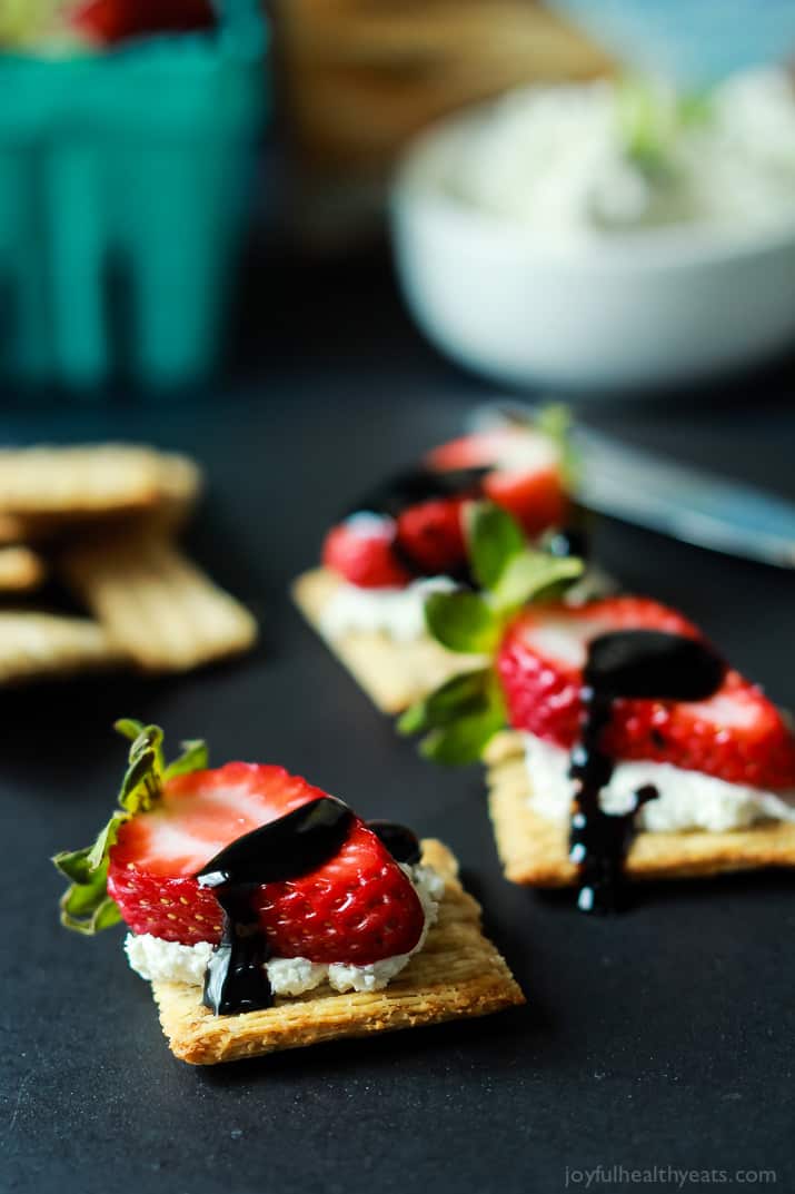 Strawberry Goat Cheese Bites on a cracker topped with a Balsamic Reduction Drizzle