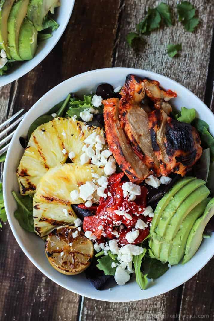 Top view of a bowl of Harissa Lime Grilled Chicken Salad with pineapple, avocado and crumbled feta