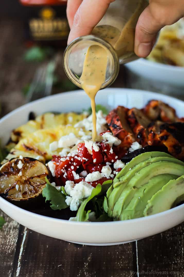 Creamy Cilantro Lime Vinaigrette being poured over Harissa Lime Grilled Chicken Salad