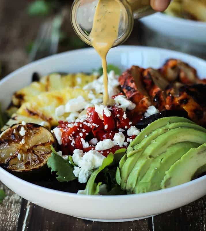 Creamy Cilantro Lime Vinaigrette being poured over Harissa Lime Grilled Chicken Salad