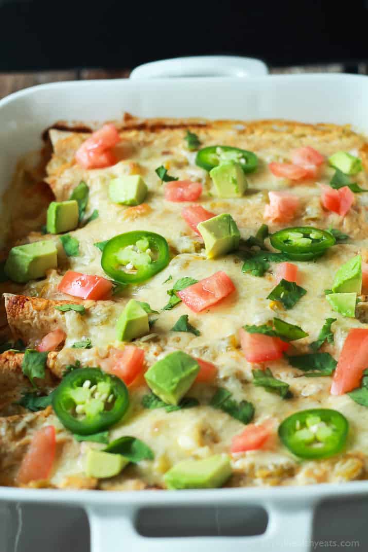 A pan of Chicken Enchiladas topped with melted cheese, jalapeno, avocado, and tomato