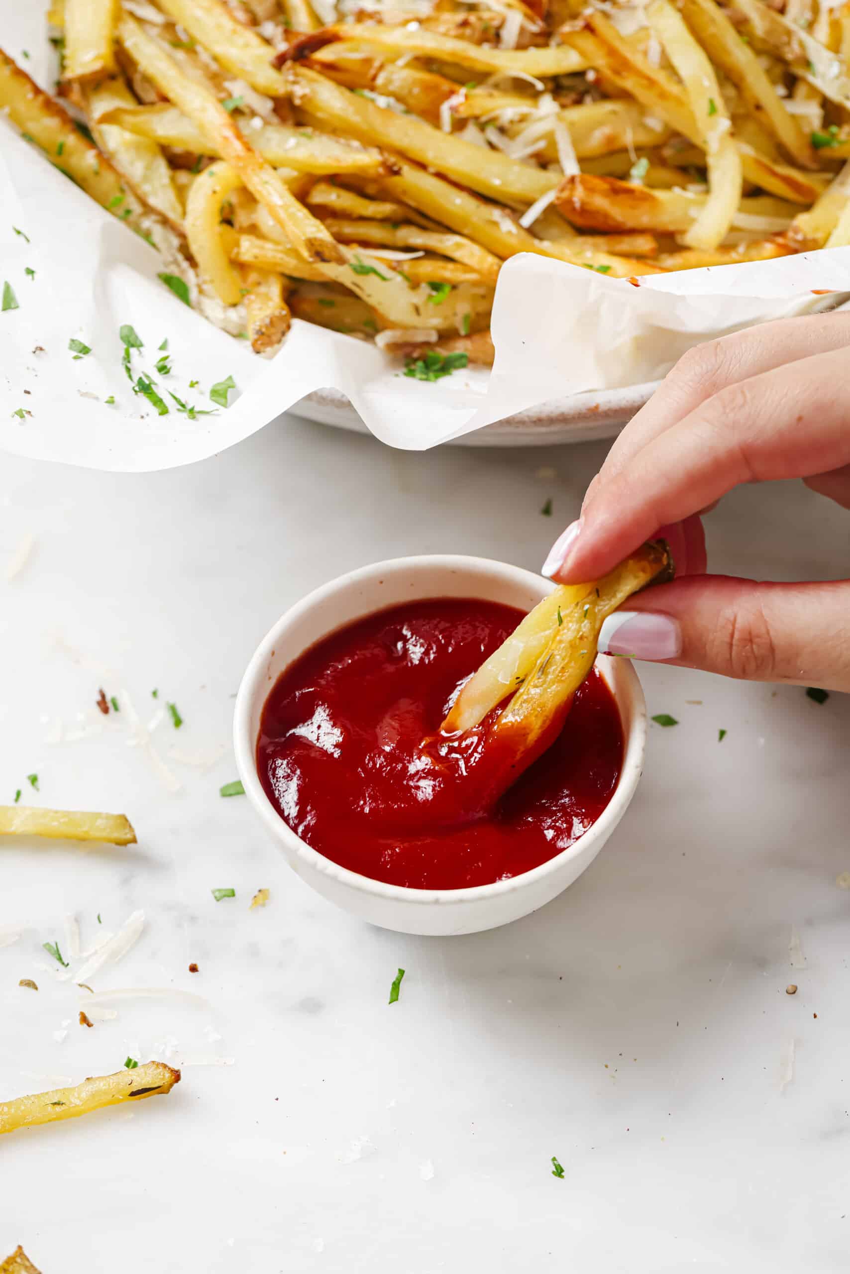 Dipping a french fry into ketchup. 