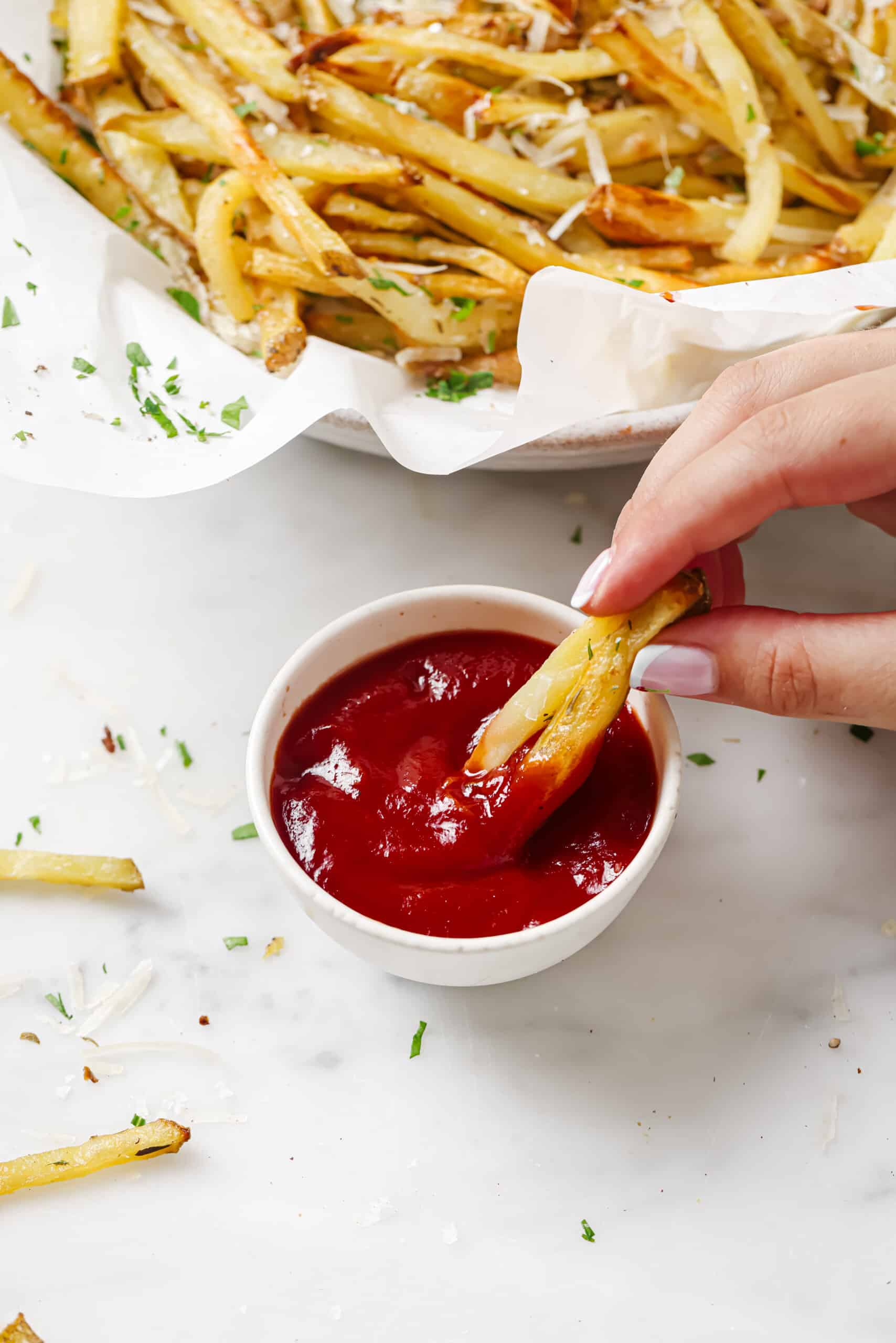 This baked garlic parmesan fries recipe is so good it might tempt you into eating the whole tray on your own. Good thing they're healthy! Dipping a french fry into ketchup.