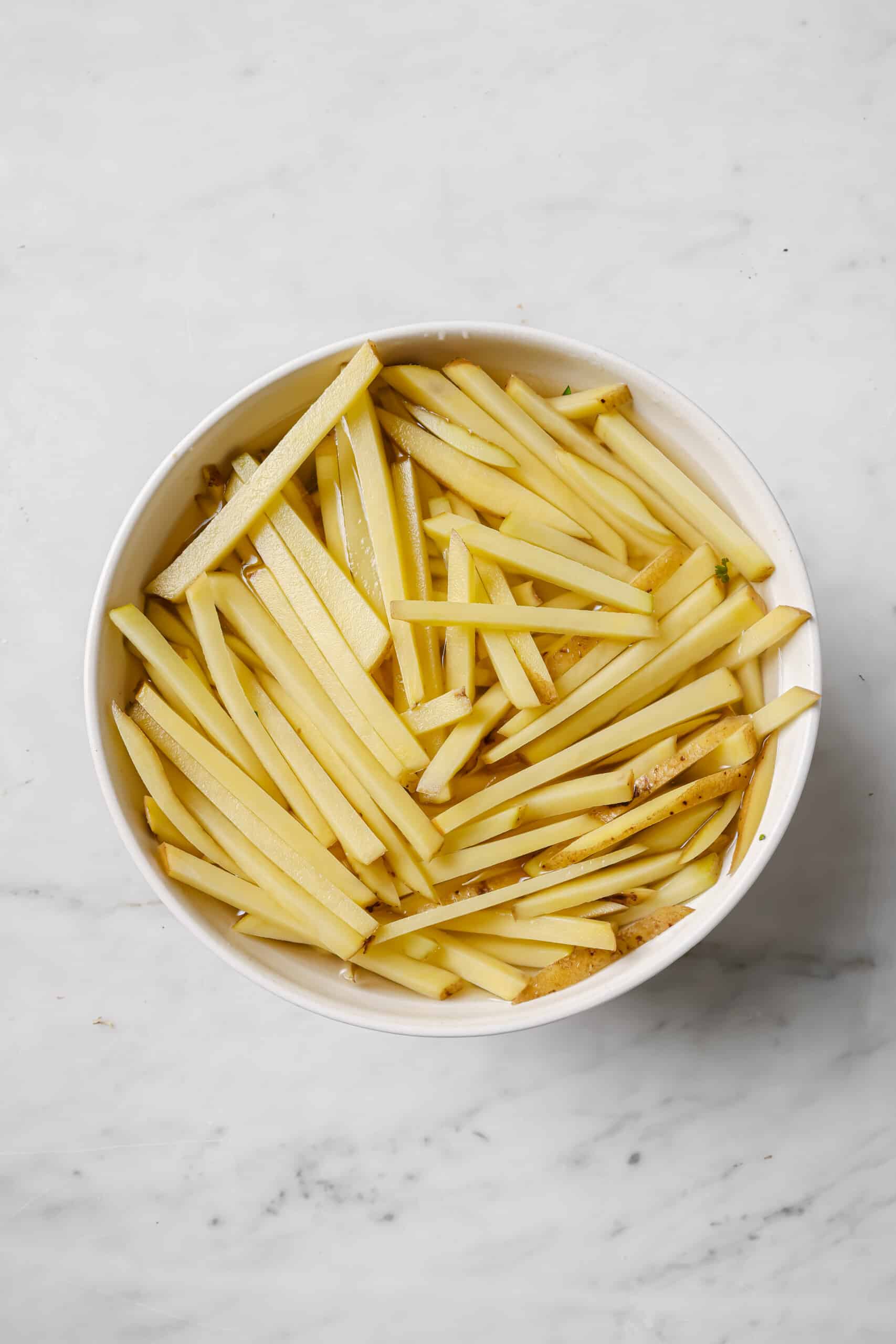 This baked garlic parmesan fries recipe is so good it might tempt you into eating the whole tray on your own. Good thing they're healthy! Soaking the potatoes.