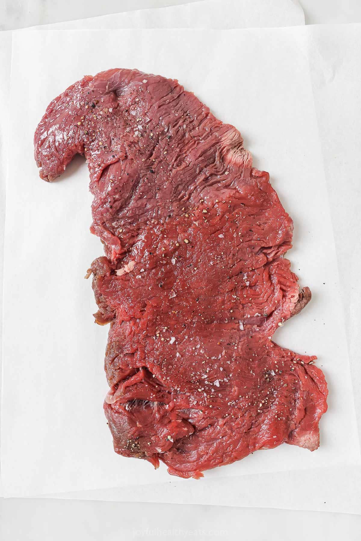 This juicy Grilled Flank Steak with Avocado Chimichurri is an easy recipe that’s full of flavor. It’s ready in less than 20 minutes! Overhead view of raw seasoned flank steak
