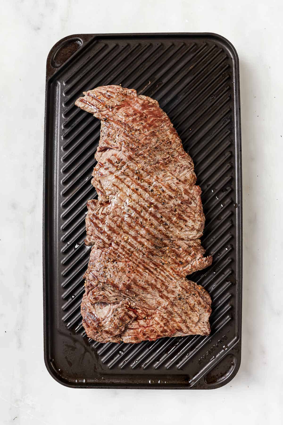 This juicy Grilled Flank Steak with Avocado Chimichurri is an easy recipe that’s full of flavor. It’s ready in less than 20 minutes! Overhead view of grilled flank steak on grill pan