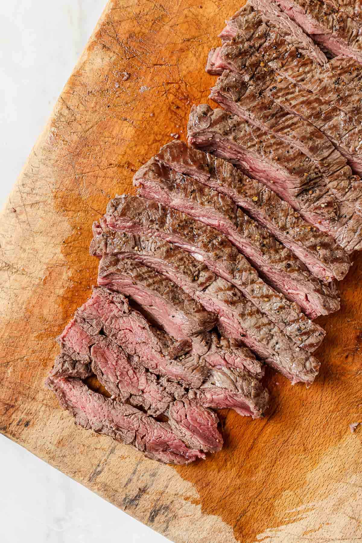 This juicy Grilled Flank Steak with Avocado Chimichurri is an easy recipe that’s full of flavor. It’s ready in less than 20 minutes! Overhead view of sliced flank steak on cutting board