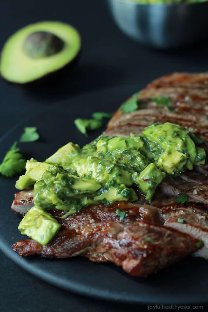 黒いプレートの上にアボカドChimichurriとグリル脇腹ステーキのクローズアップ