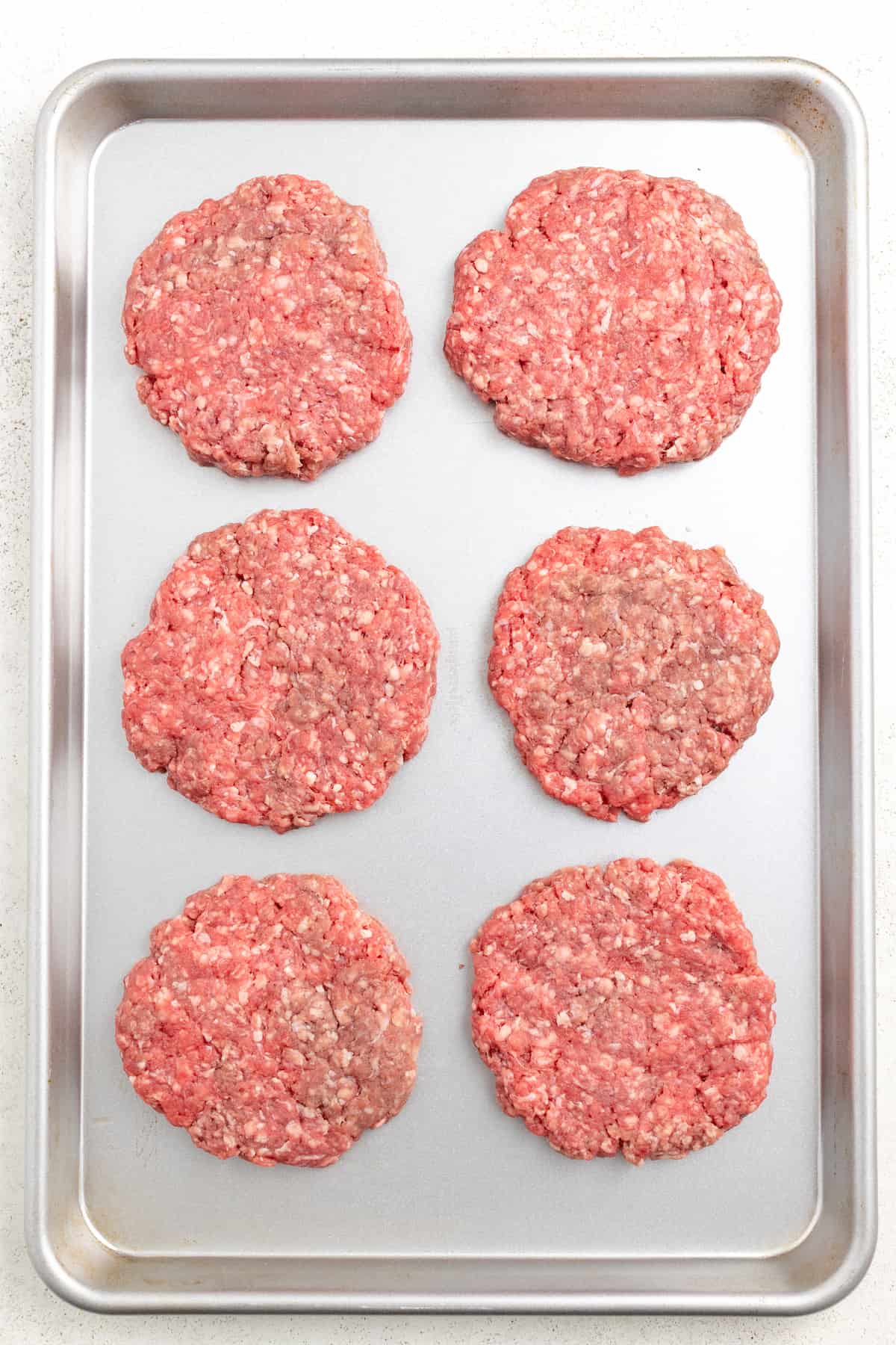 This 15-minute Italian cheeseburger is loaded with gouda cheese, sun-dried tomatoes, pesto aioli, and prosciutto for the perfect bite. Formed patties on a baking sheet.