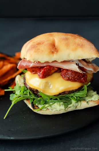 A juicy Italian Cheeseburger served on a toasted ciabatta bun, topped with smoked gouda cheese, spicy arugula, sun dried tomatoes, salty prosciutto, and basil pesto aioli! Done in 15 minutes this Burger is sure to be your new favorite this summer! | joyfulhealthyeats.com #recipes #grill #easy