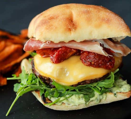 A juicy Italian Cheeseburger served on a toasted ciabatta bun, topped with smoked gouda cheese, spicy arugula, sun dried tomatoes, salty prosciutto, and basil pesto aioli! Done in 15 minutes this Burger is sure to be your new favorite this summer! | joyfulhealthyeats.com #recipes #grill #easy