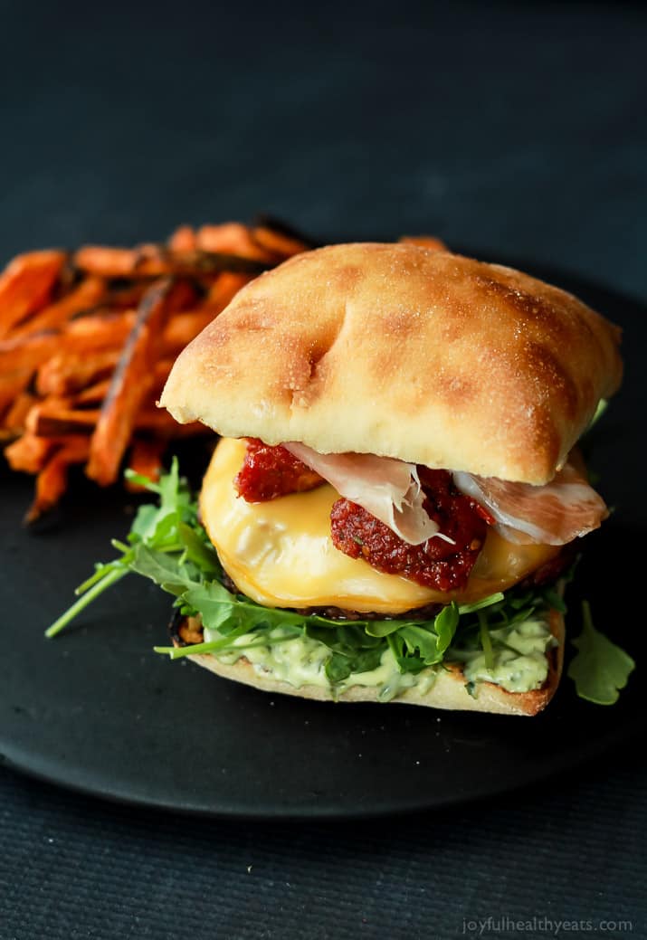 A juicy Italian Cheeseburger served on a toasted ciabatta bun, topped with smoked gouda cheese, spicy arugula, sun dried tomatoes, salty prosciutto, and basil pesto aioli! Done in 15 minutes this Burger is sure to be your new favorite this summer! | joyfulhealthyeats.com #recipes #grill #easy