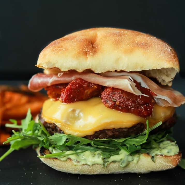 A juicy Italian Cheeseburger served on a toasted ciabatta bun, topped with smoked gouda cheese, spicy arugula, sun dried tomatoes, salty prosciutto, and basil pesto aioli! Done in 15 minutes this Burger is sure to be your new favorite this summer! | joyfulhealthyeats.com #recipes #grill #easy