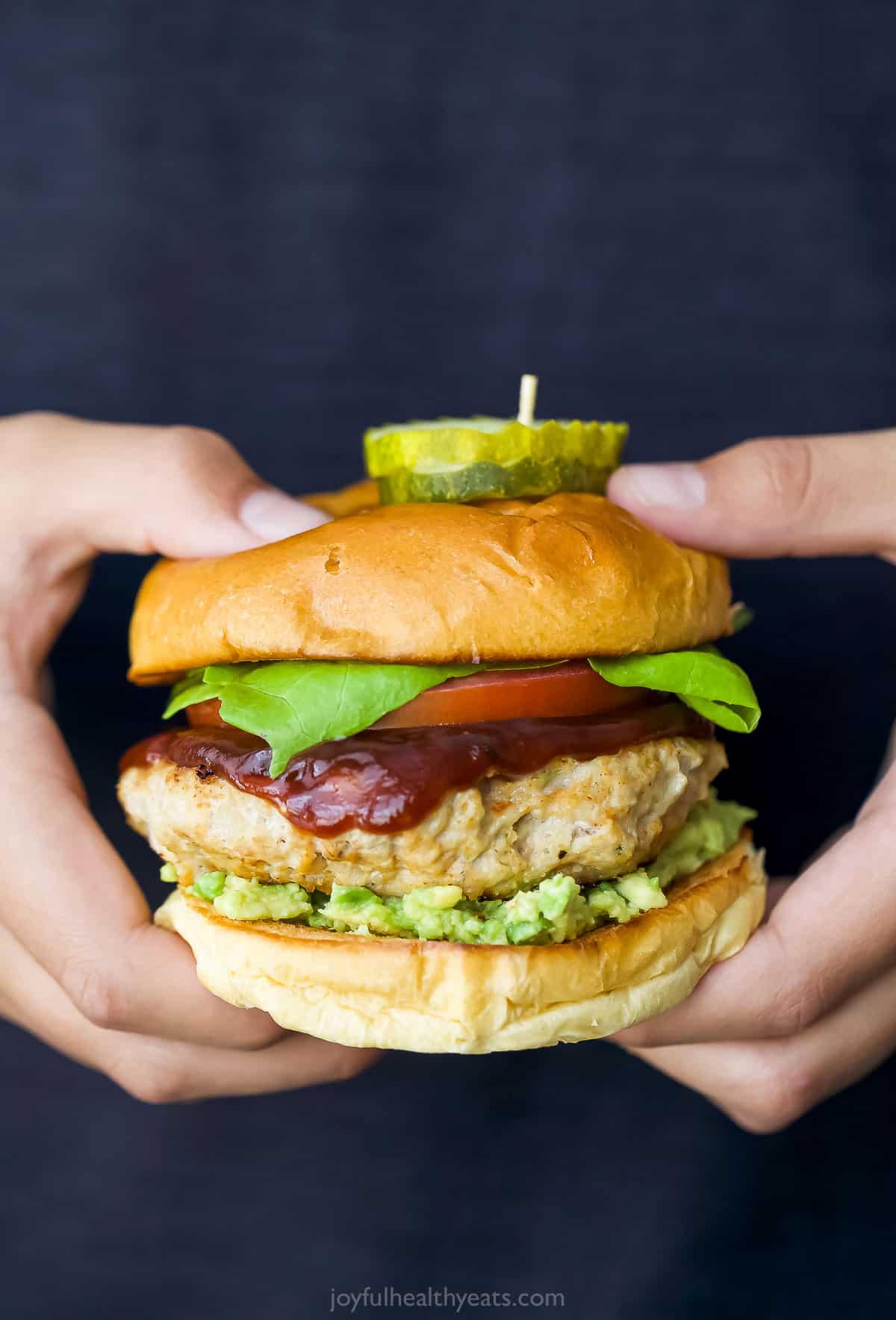 These BBQ Chicken Burgers are easy to make and perfect for summer parties and weeknight dinners. So flavorful and juicy! Two hands holding BBQ chicken burger