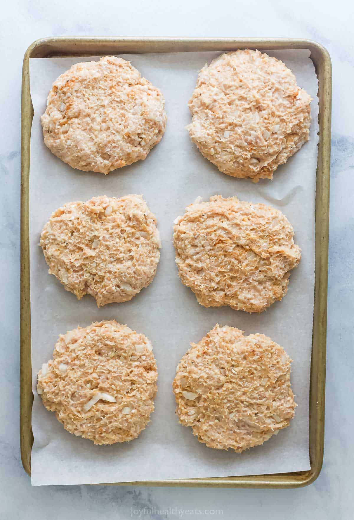 These BBQ Chicken Burgers are easy to make and perfect for summer parties and weeknight dinners. So flavorful and juicy! Overhead view of chicken burger patties on parchment-lined sheet pan