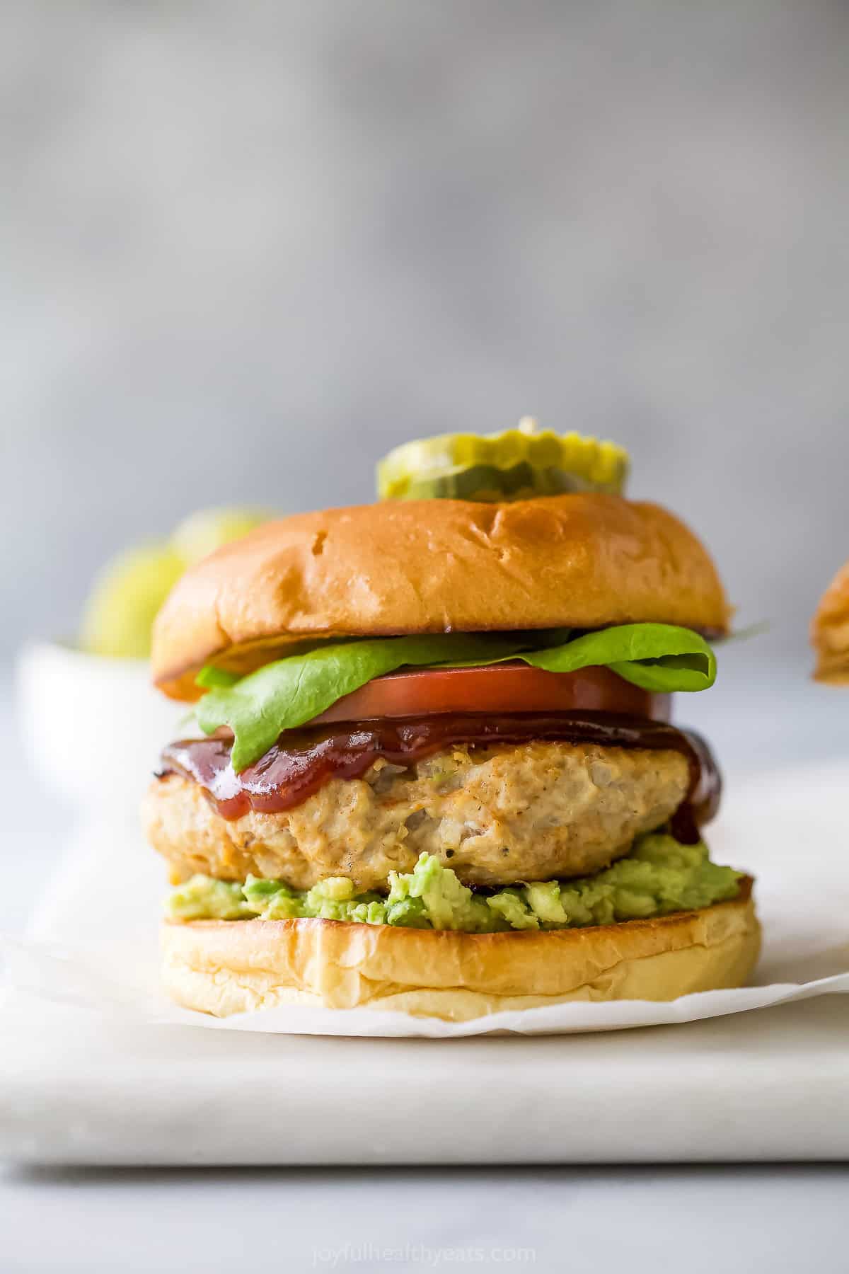 These BBQ Chicken Burgers are easy to make and perfect for summer parties and weeknight dinners. So flavorful and juicy! Chicken burger on brioche bun with lettuce, tomato, BBQ sauce, and mashed avocado