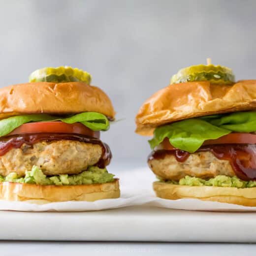 Two BBQ chicken burgers on parchment-lined marble board