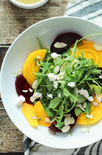 Roasted Beet Arugula Salad with sliced almonds, fresh thyme, and creamy goat cheese then drizzled with a honey dijon vinaigrette - the perfect light salad for your weekend party! Takes minutes to make! | joyfulhealthyeats.com #recipes #vegetarian #glutenfree