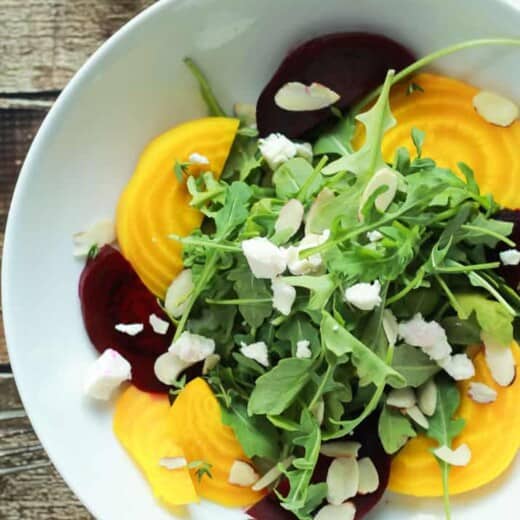 Roasted Beet Arugula Salad with sliced almonds, fresh thyme, and creamy goat cheese then drizzled with a honey dijon vinaigrette - the perfect light salad for your weekend party! Takes minutes to make! | joyfulhealthyeats.com #recipes #vegetarian #glutenfree