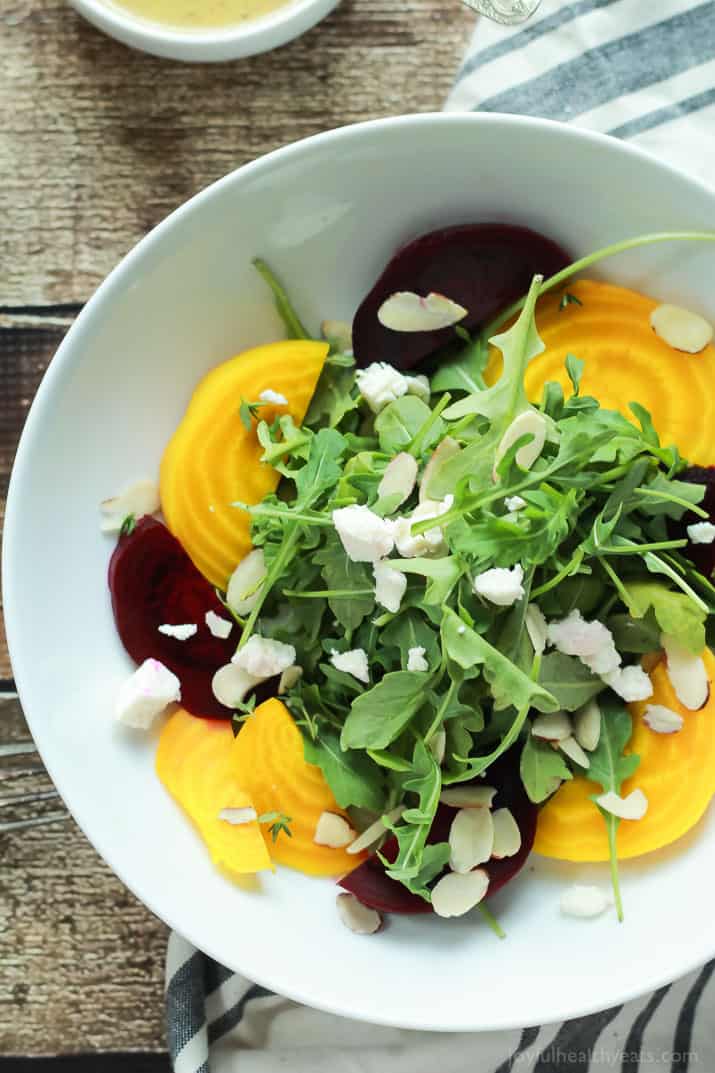 Roasted Beet Arugula Salad with sliced almonds, fresh thyme, and creamy goat cheese then drizzled with a honey dijon vinaigrette - the perfect light salad for your weekend party! Takes minutes to make! | joyfulhealthyeats.com #recipes #vegetarian #glutenfree