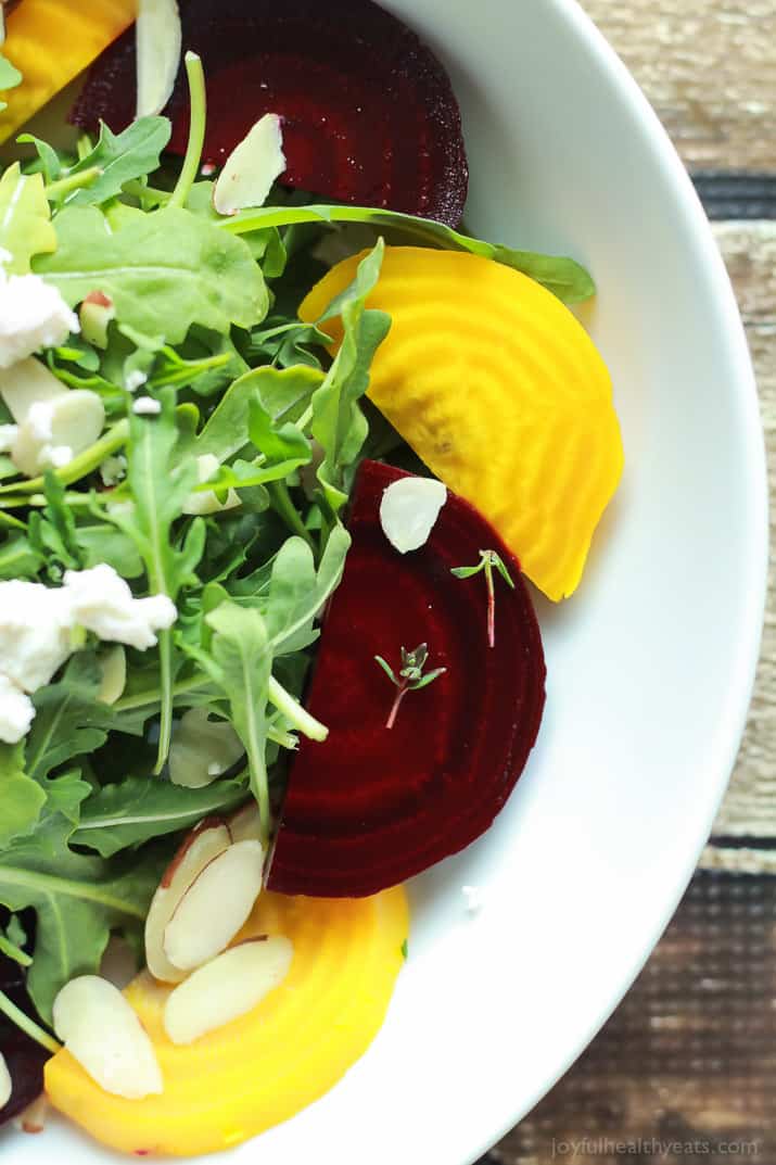 Roasted Beet Arugula Salad with sliced almonds, fresh thyme, and creamy goat cheese then drizzled with a honey dijon vinaigrette - the perfect light salad for your weekend party! Takes minutes to make! | joyfulhealthyeats.com #recipes #vegetarian #glutenfree