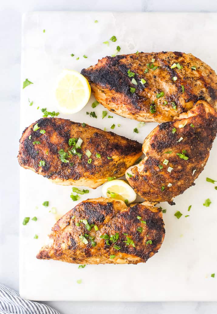 grilled whole chicken breasts garnished with fresh herbs