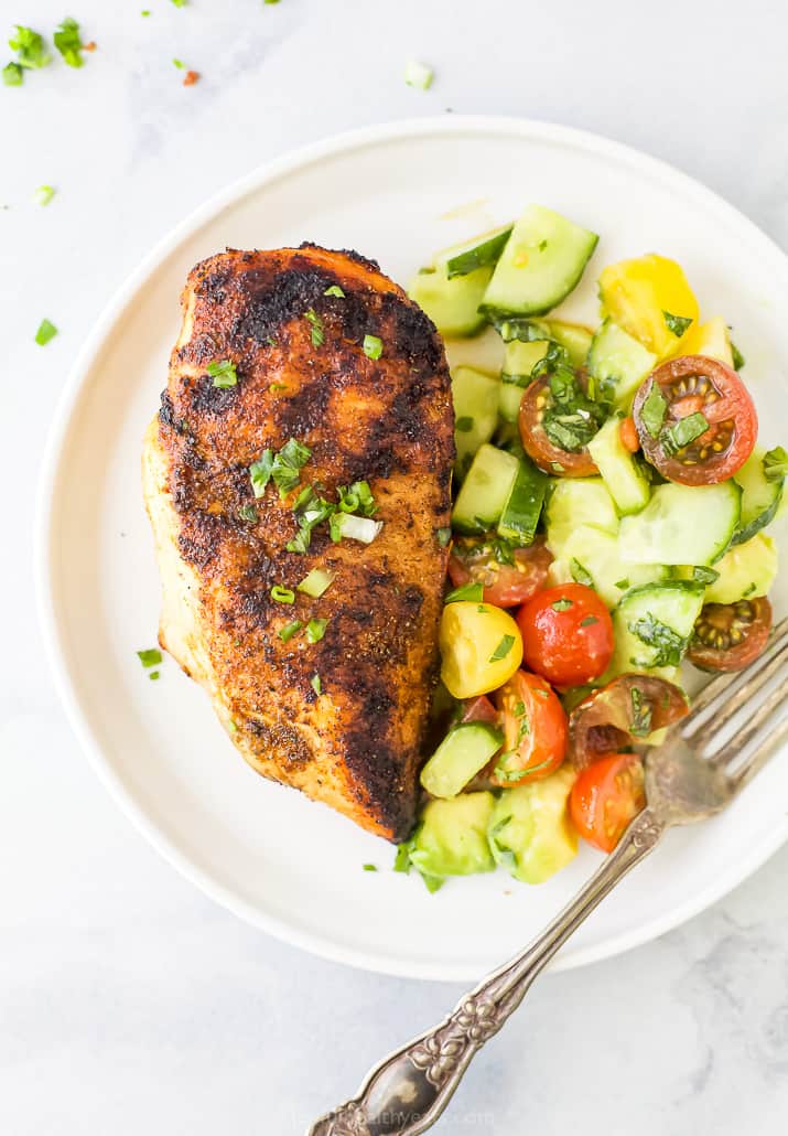grilled chicken breast on a plate with a cucumber salad
