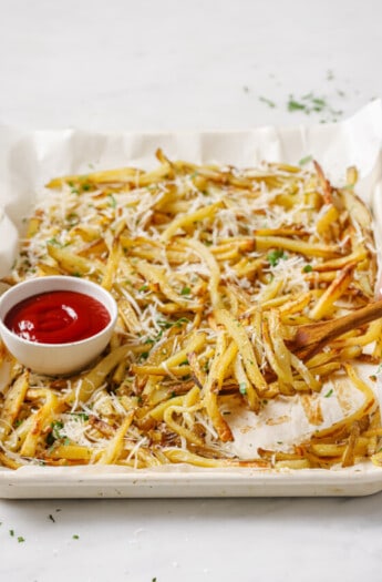 A tray of crispy fries with ketchup on the side.