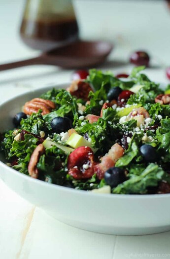 A Summer Kale Salad Recipe that will blow your mind! Filled with fresh cherries and blueberries for some sweet then countered with salty bacon and feta. Perfect for a backyard bbq party this summer, its even Red White and Blue! | joyfulhealthyeats.com #recipe