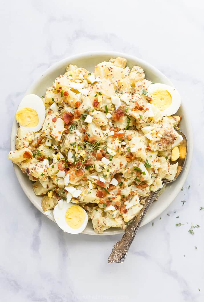 overhead photo of creamy easy potato salad recipe with bacon on a plate with a spoon