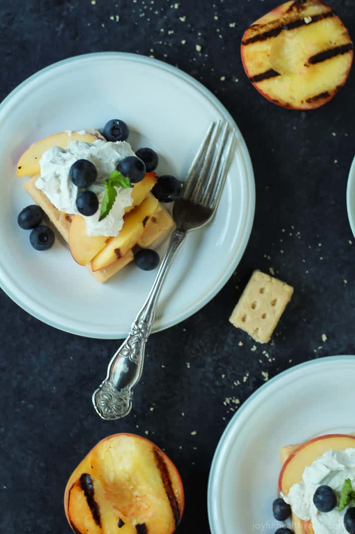 Top view of a plate of Grilled Peach Shortcake with buttery shortbread, grilled peaches, and coconut whipped cream and fresh blueberries