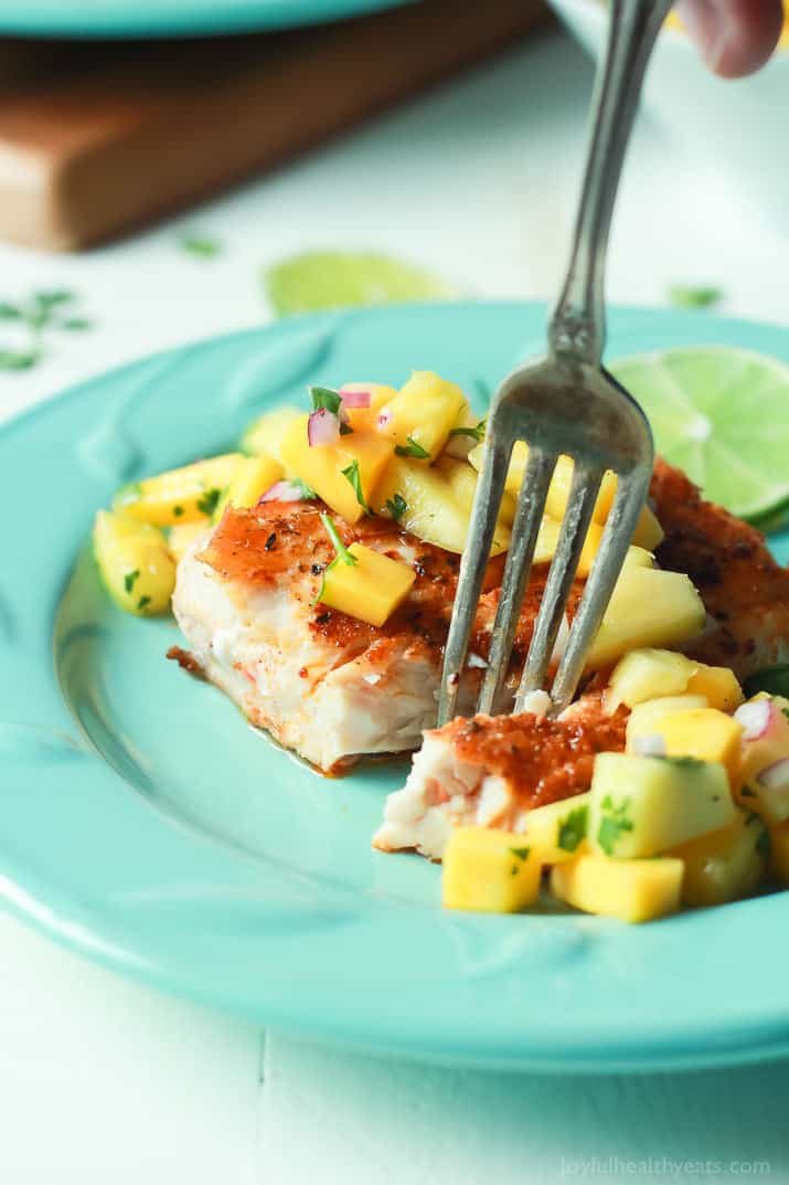 A fork spearing Pan Seared Cajun Mahi Mahi with a fresh Mango Pineapple Salsa on a plate