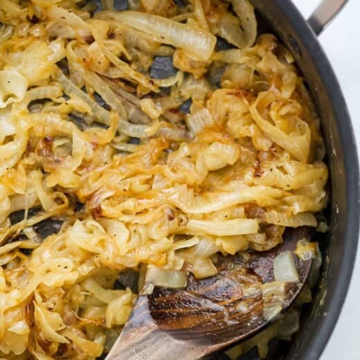 Caramelized onions in skillet with wooden spoon.