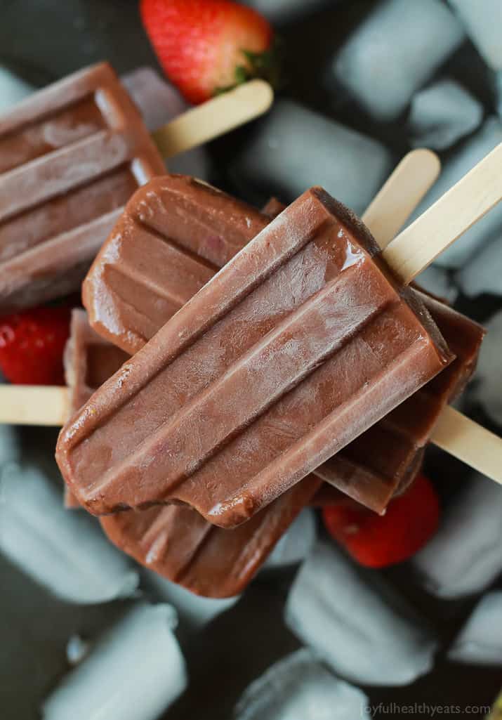 A pile of chocolate banana popsicles on top of a layer of ice cubes