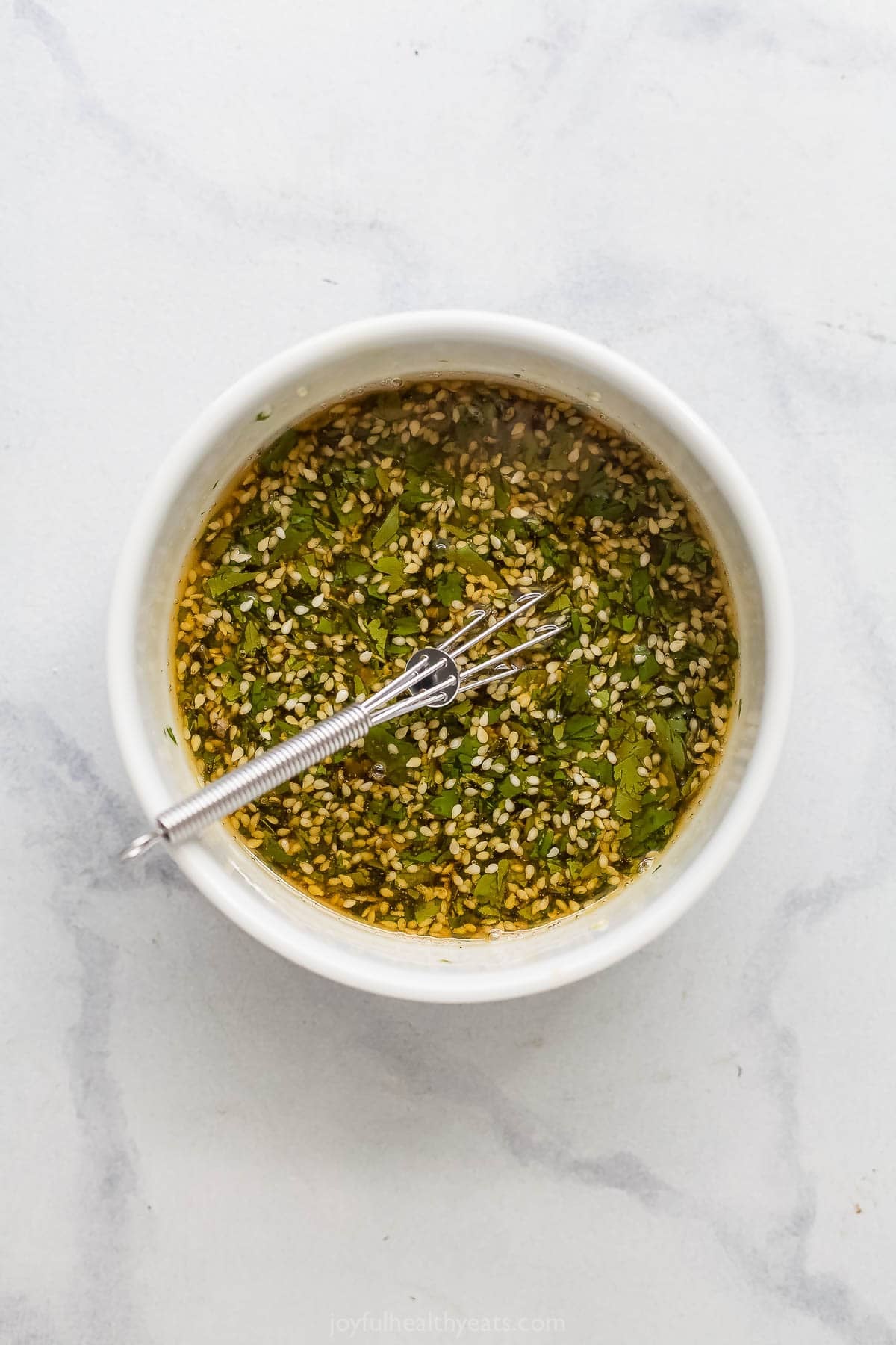 Bowl of sesame vinaigrette with whisk.