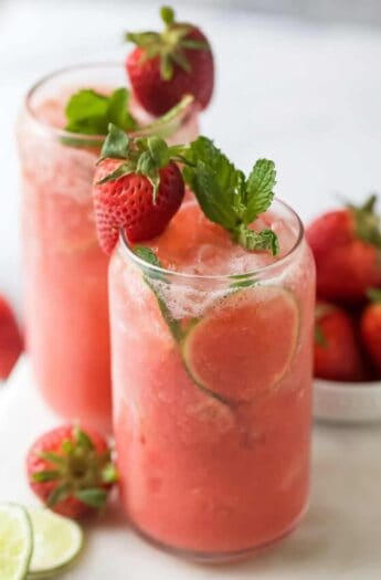 Strawberry limeade in a glass with mint and strawberry garnishes.