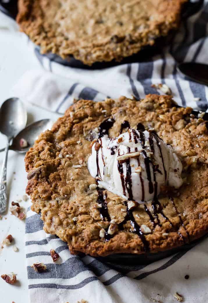 a large skillet cookie with ice cream on top and drizzle of chocolate sauce