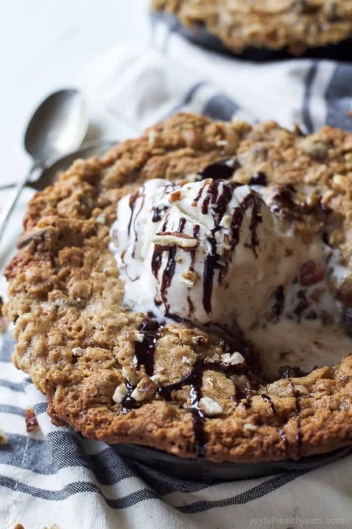 Close-up of Coconut Oatmeal Chocolate Chip Skillet Cookie topped with vanilla ice cream and chocolate drizzle