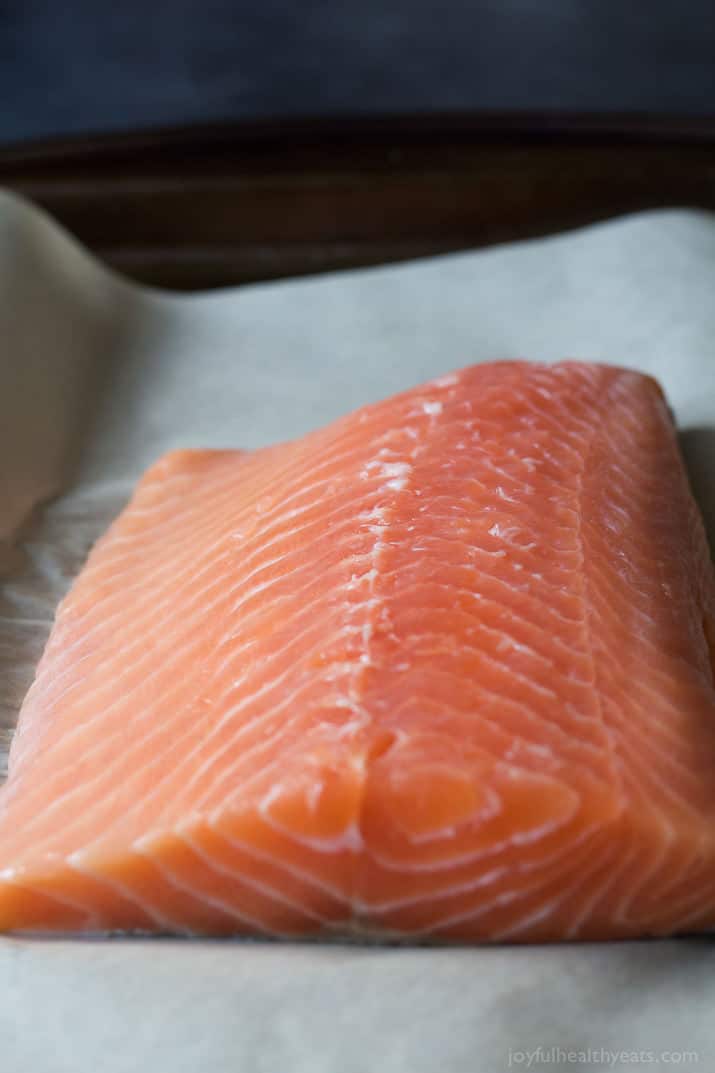 A raw salmon fillet on parchment paper