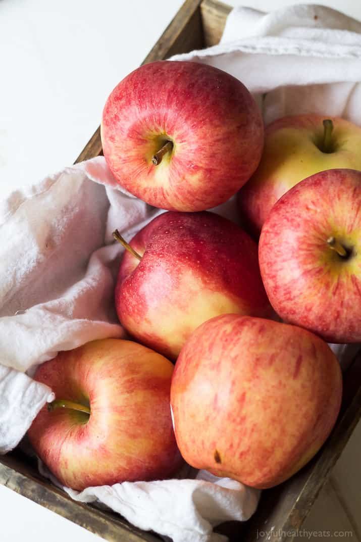 Top view of apples in a wooden box with a tea towel