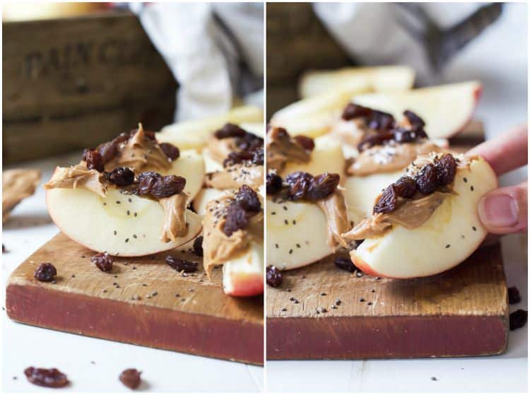 Apple wedges with peanut butter, dried cranberries and chia seeds on a wooden cutting board