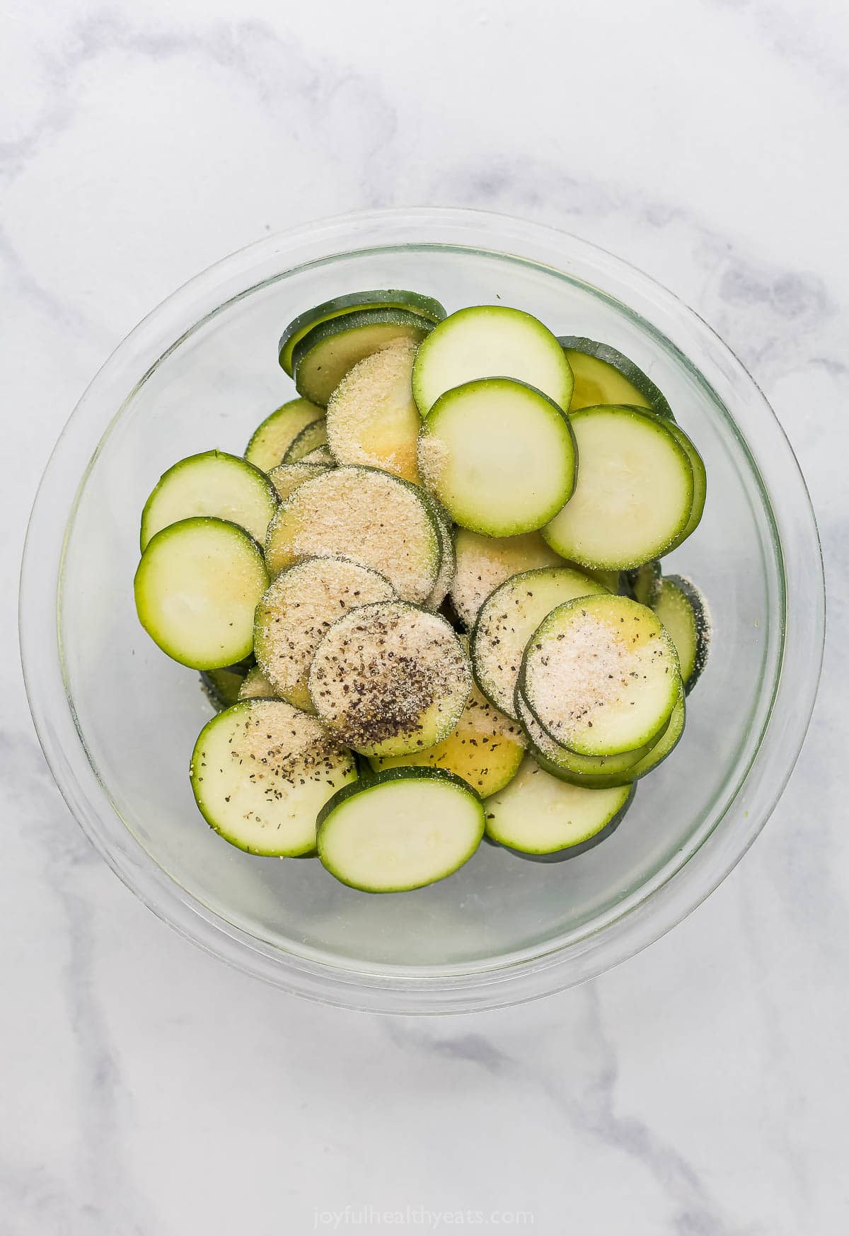 Overhead view of seasonings added to zucchini chips in bowl