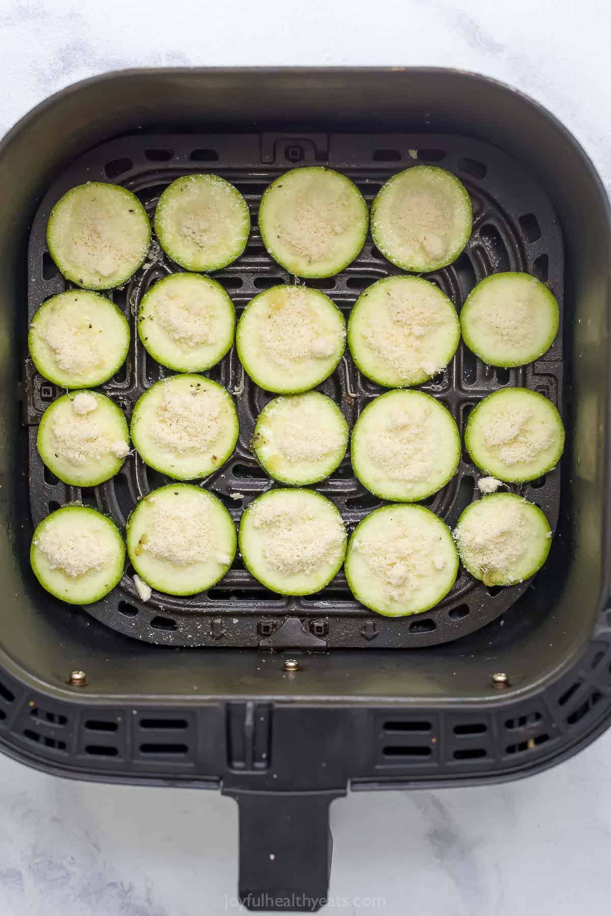 Overhead view of uncooked zucchini chips in air fryer