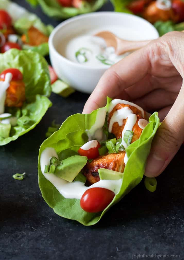 Grilled Buffalo Chicken Lettuce Wrap being held next to a bowl of creamy dressing